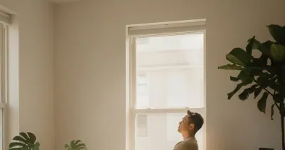 شخص يجلس بهدوء في ضوء طبيعي ويكتب في دفتر للتأمل وتنظيم الأفكار