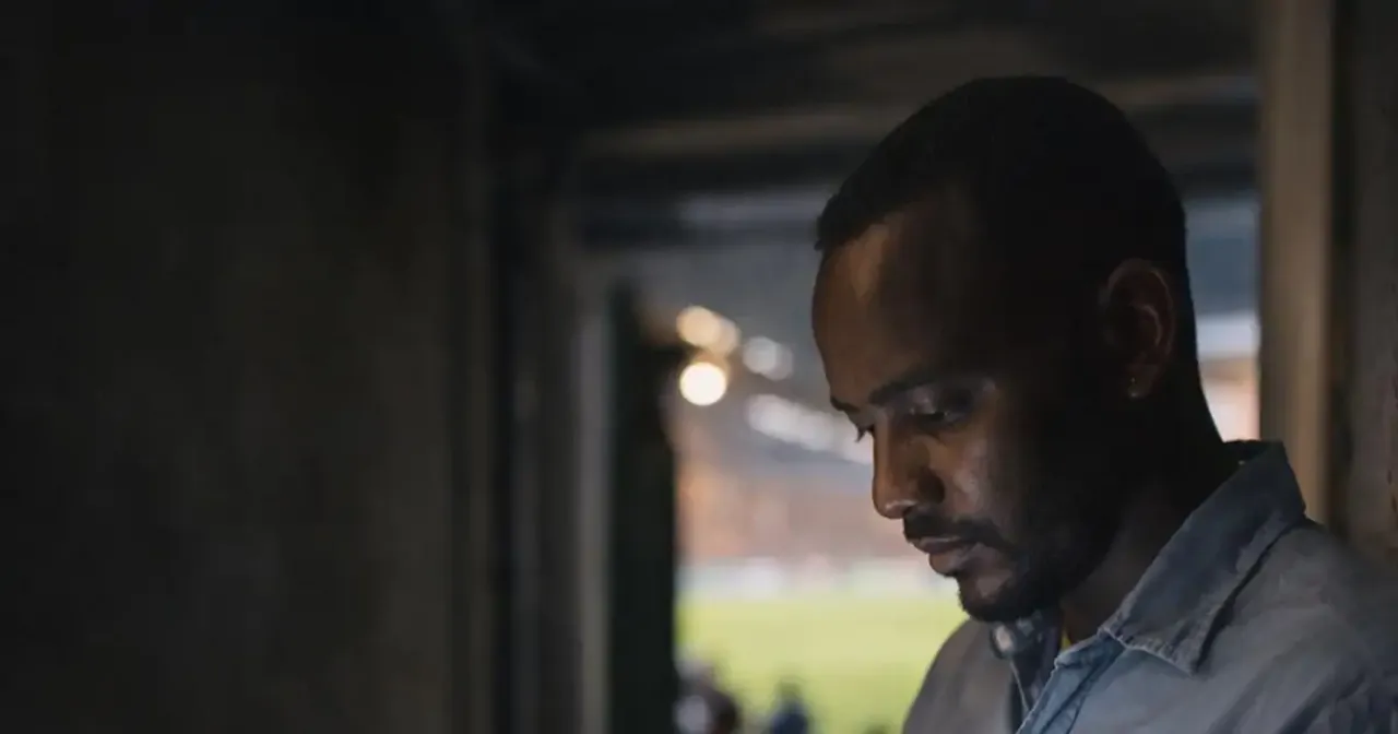 Sudanese football journalist checking transfer news near a stadium