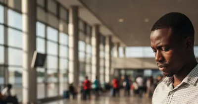 مسافر يقف في مطار أفريقي يحمل جواز سفر